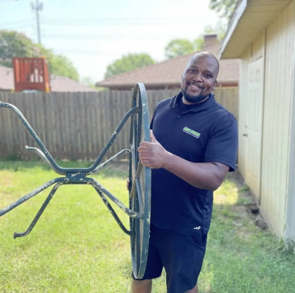 Junk Geeks professional removing an outdoor table from a yard during junk removal services in hurst tx
